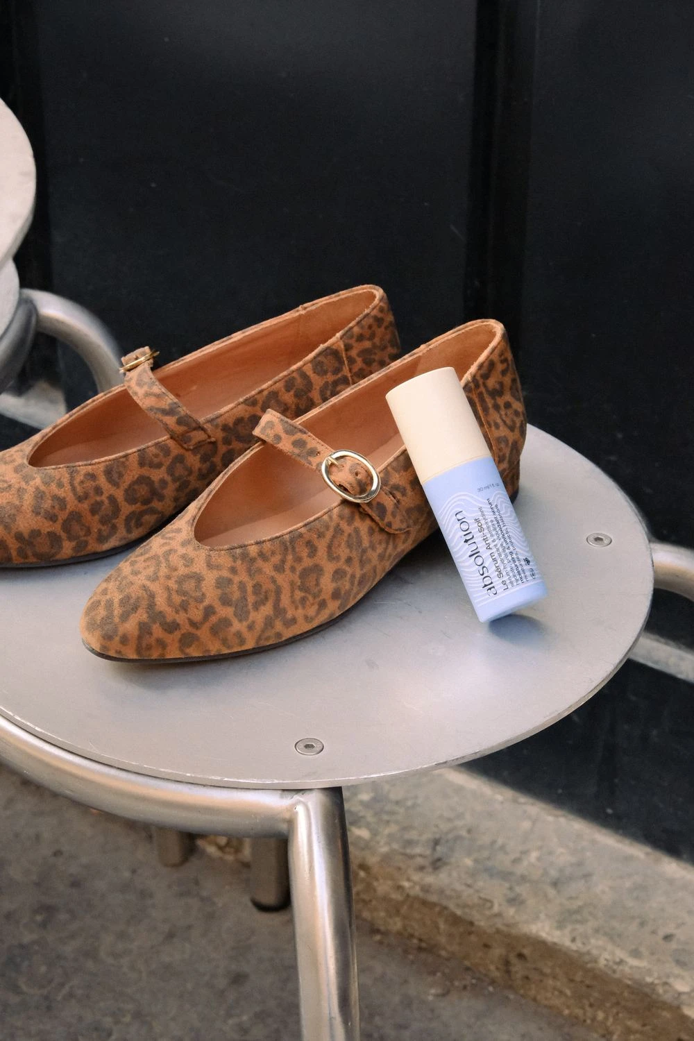 Ballerines Cassandre léopard et Sérum Anti-Soif Absolution sur une table de terrasse parisienne