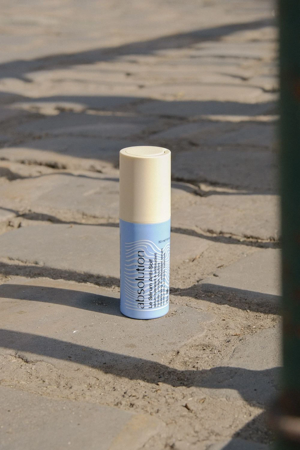 Le Sérum Anti-Soif Absolution 30 ml, format voyage, posé sur une pierre au soleil