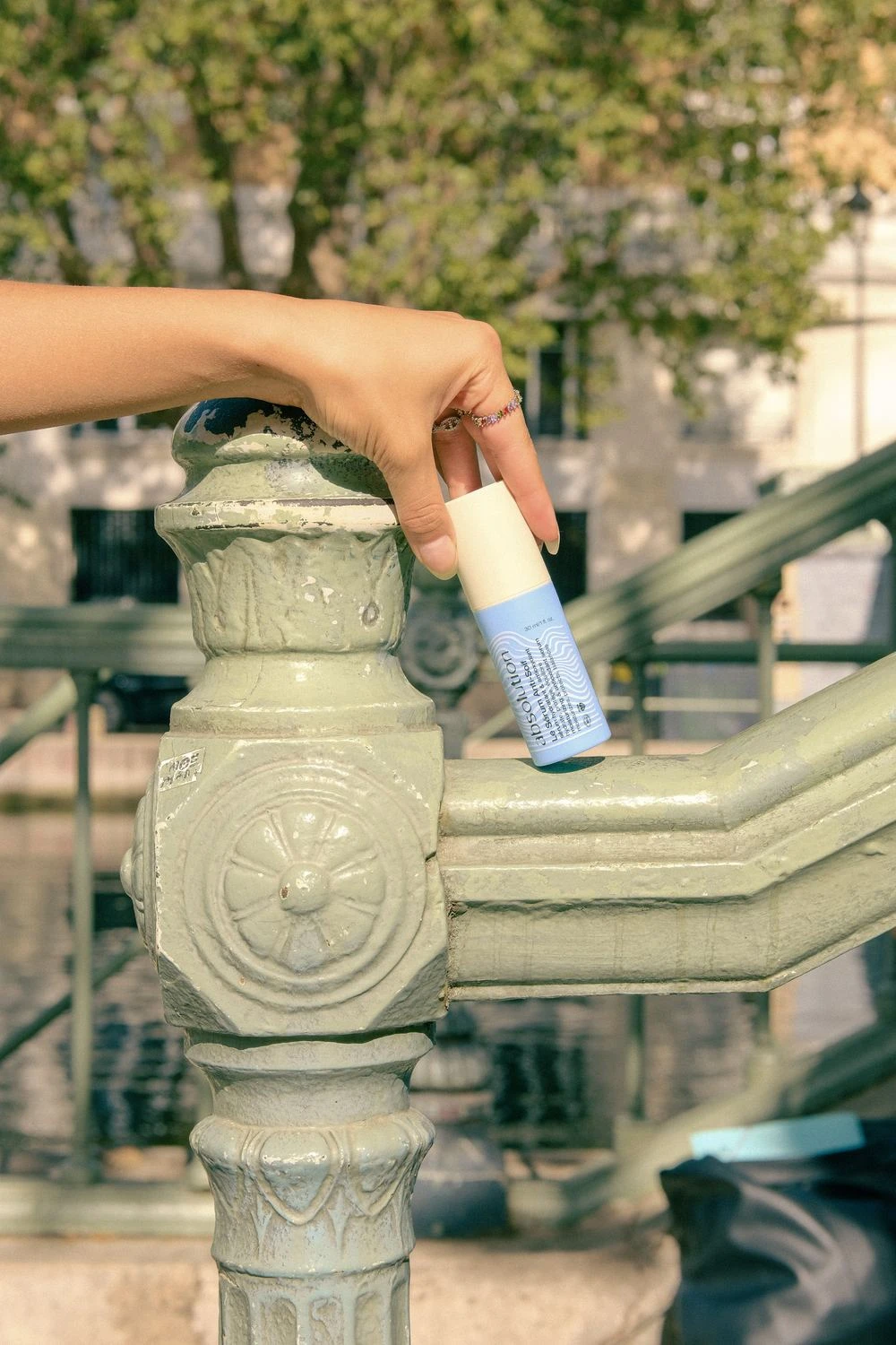 Une main pose le Sérum Anti-Soif Absolution sur une fontaine Wallace