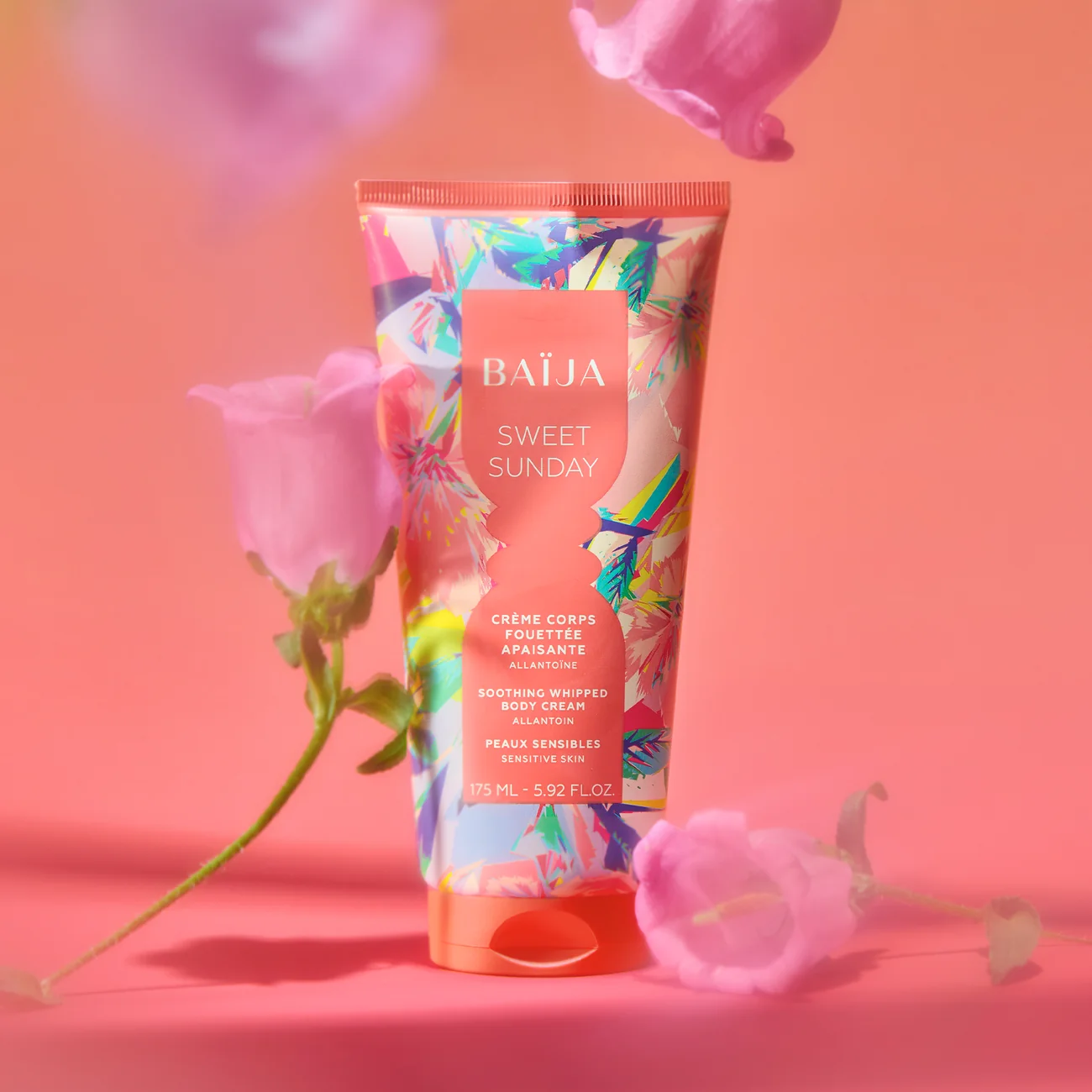 Tube de Crème Corps Sweet Sunday Baïja entouré de fleurs roses